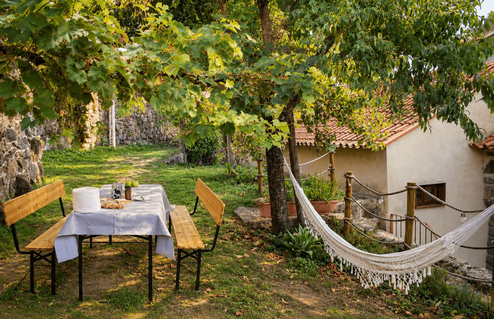 Mesa de piquenique e rede no jardim, à sombra das árvores